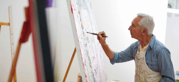 En man som målare en tavla på ett staffli